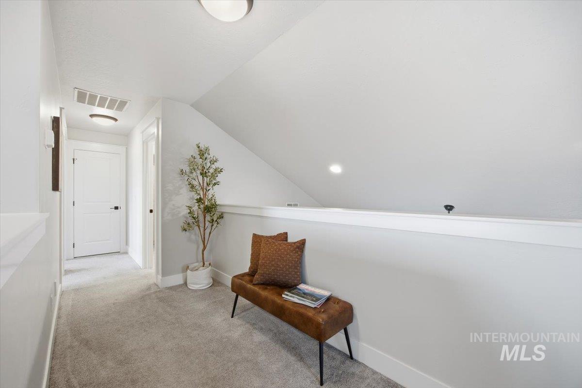Hall with light colored carpet and lofted ceiling