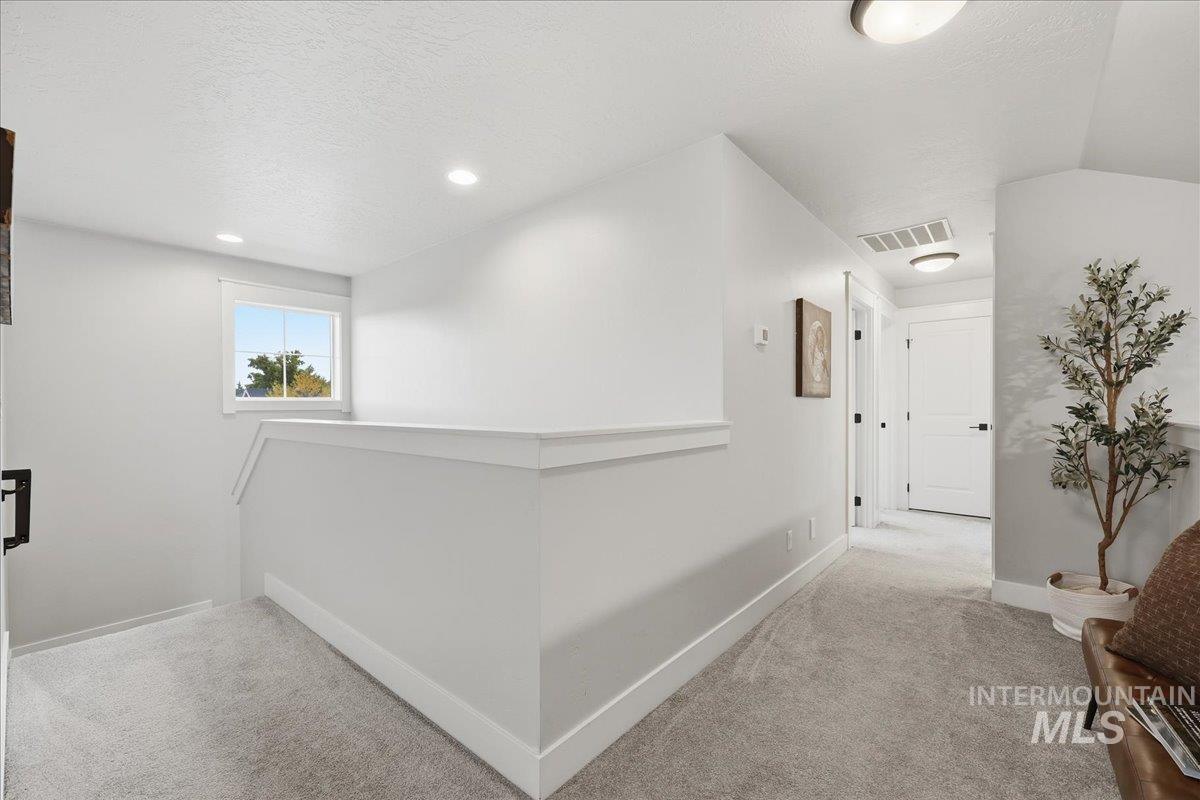 Hallway featuring a textured ceiling, carpet floors, an upstairs landing, and recessed lighting