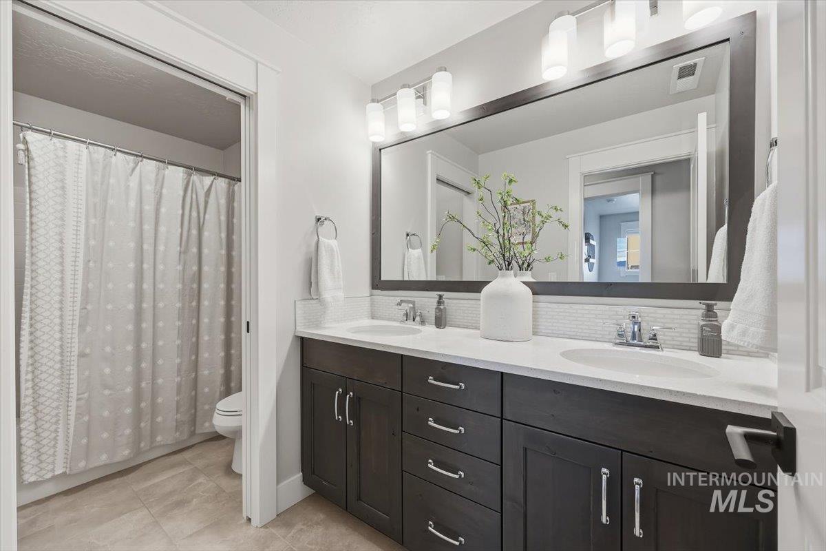 Bathroom with double vanity, a shower with curtain, and backsplash