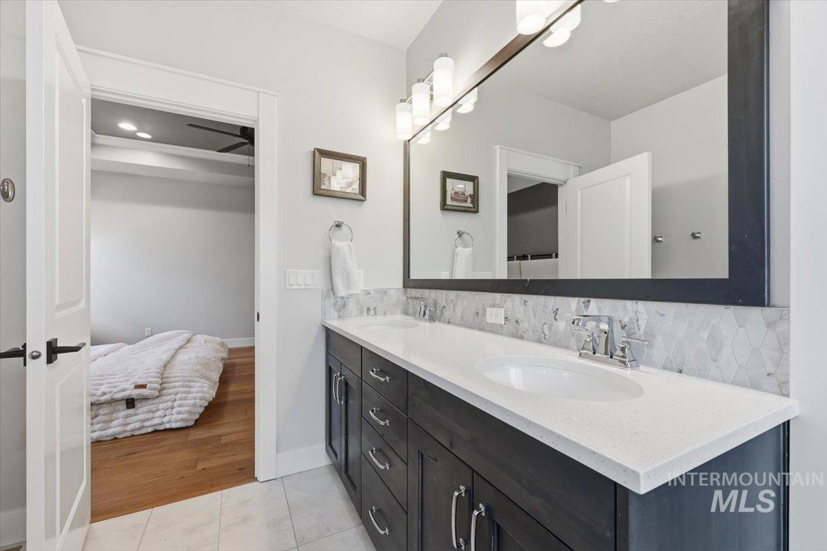 Bathroom with double vanity, light tile patterned floors, tasteful backsplash, ensuite bathroom, and recessed lighting