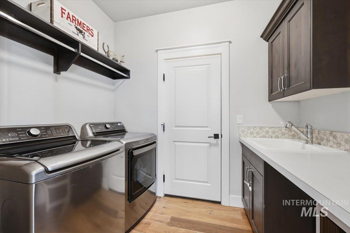 Washroom featuring light wood-style flooring, washing machine and clothes dryer, and cabinet space
