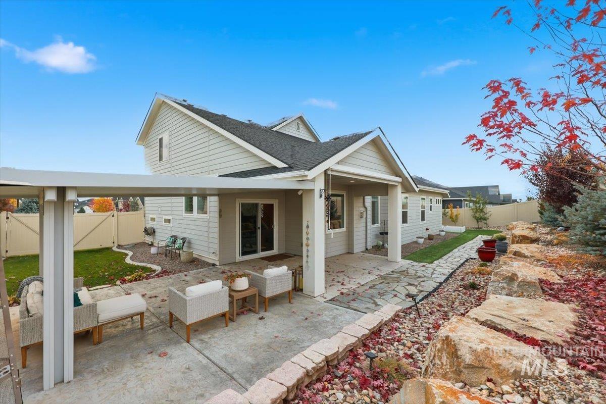 Back of property with a fenced backyard, a patio area, a shingled roof, and an outdoor living space