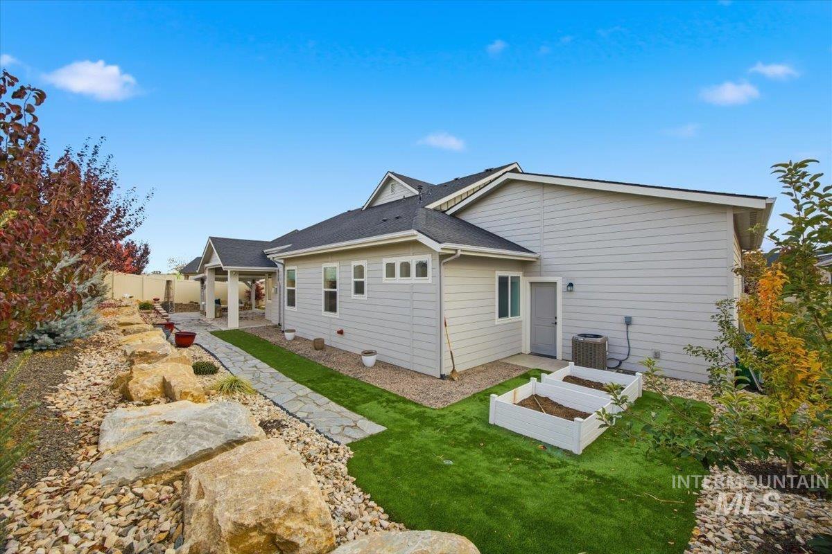 Back of house with a patio area, a garden, a fenced backyard, and roof with shingles