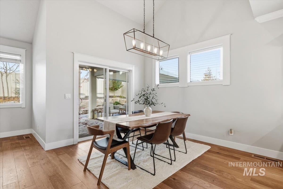 Dining space featuring light wood-style flooring, plenty of natural light, and high vaulted ceiling