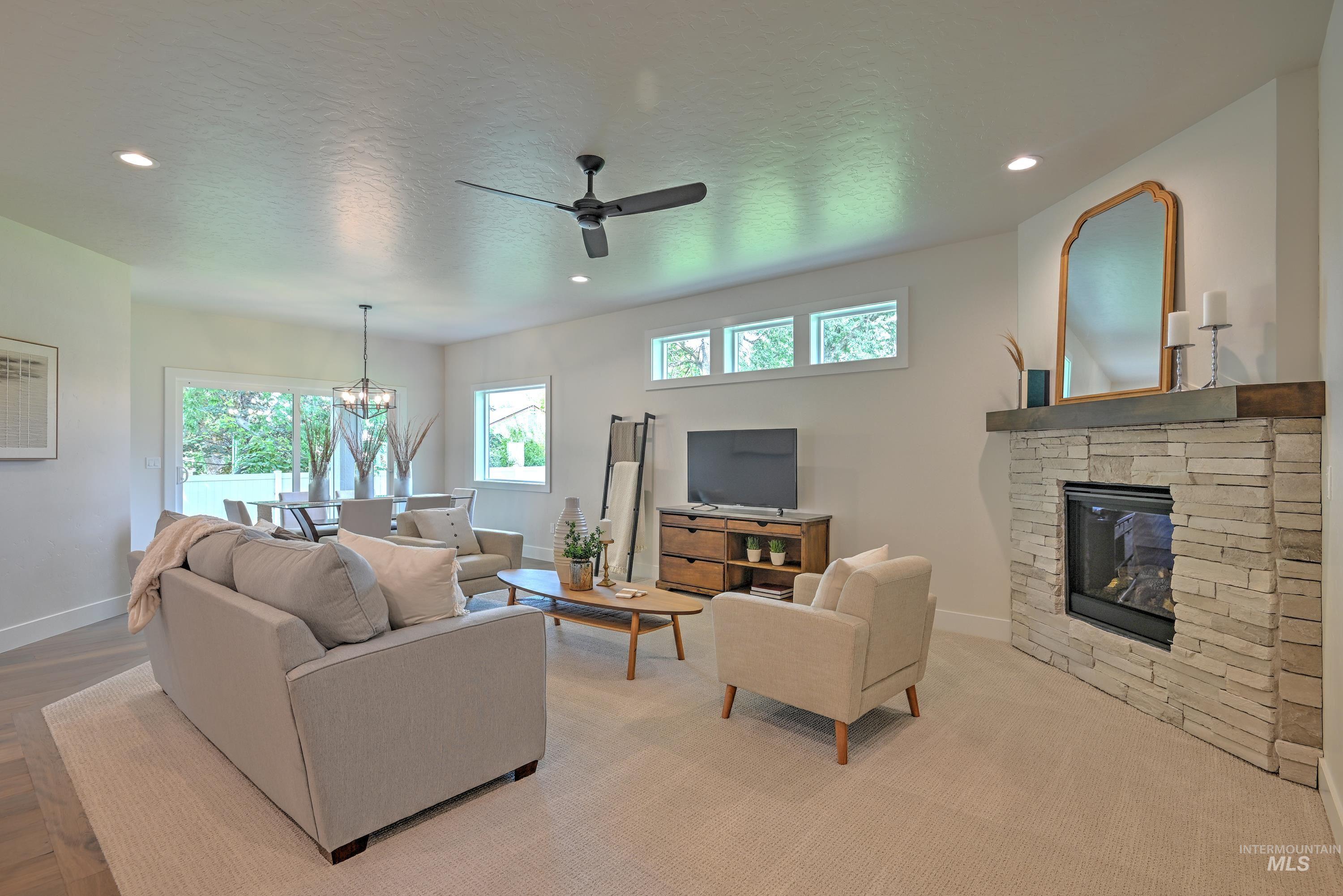 Living room with recessed lighting, ceiling fan, a stone fireplace w/mantle, a chandelier, and a textured ceiling