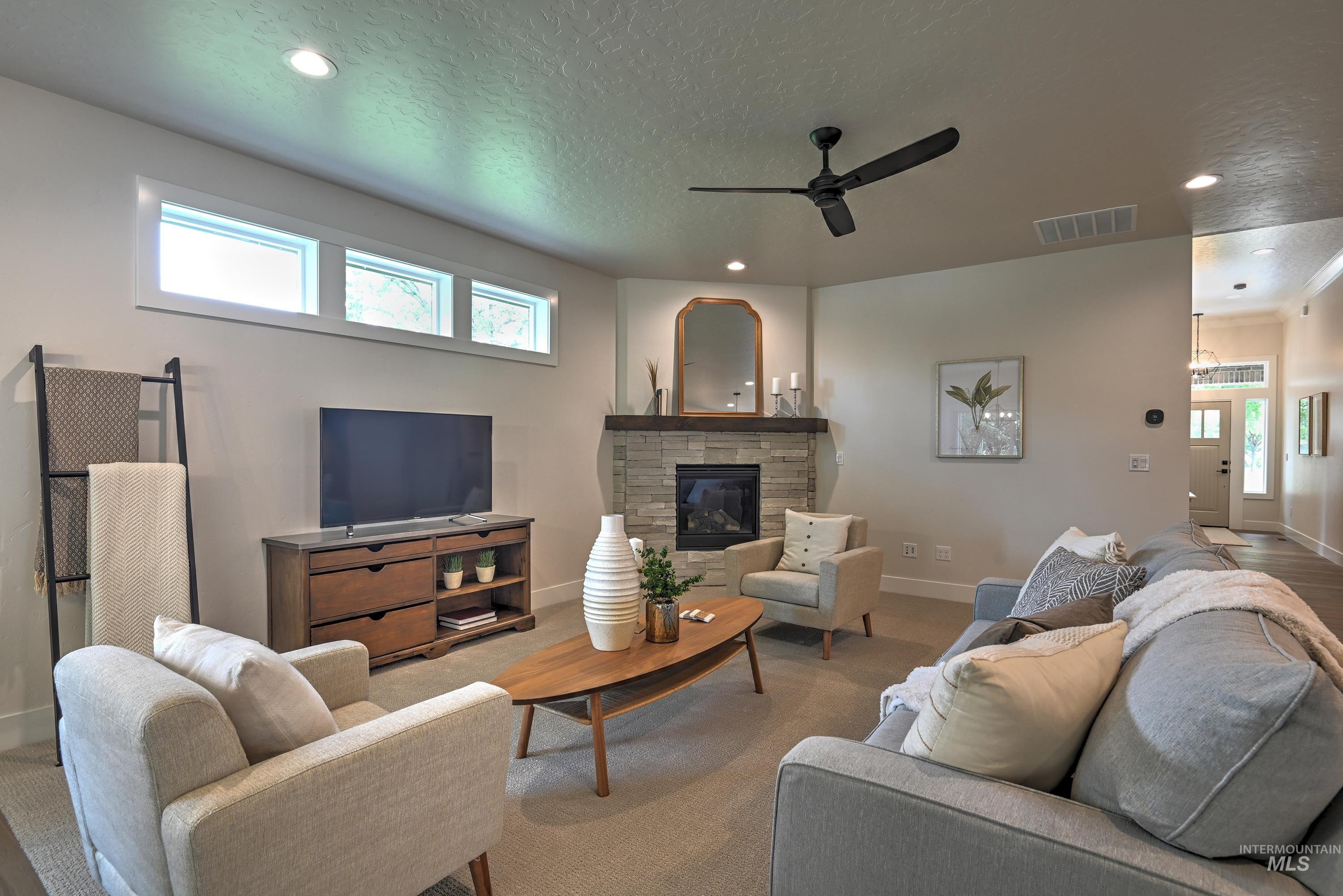 Living room featuring plenty of natural light, ceiling fan, recessed lighting, a textured ceiling, and a fireplace w/mantle