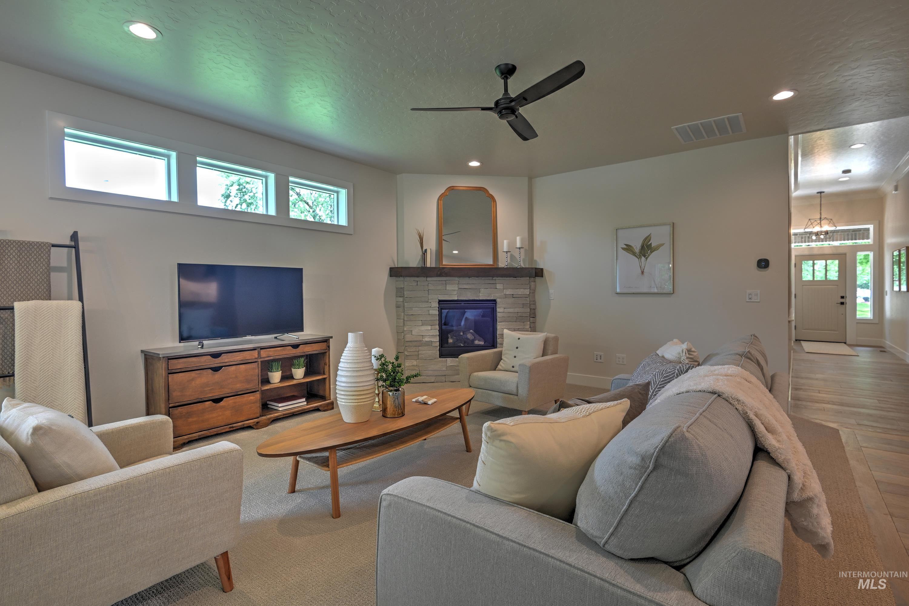 Living area with a ceiling fan, recessed lighting, a textured ceiling, a fireplace w/mantle, and wood finished floors