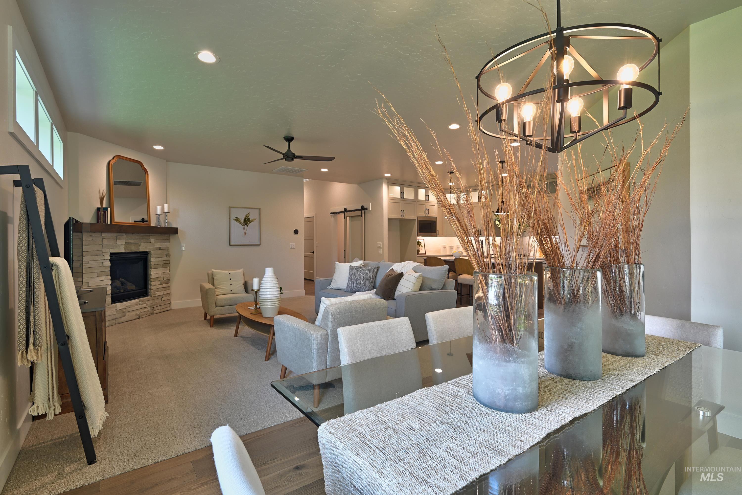 Dining area featuring a chandelier, wood finished floors, a stone fireplace, and recessed lighting