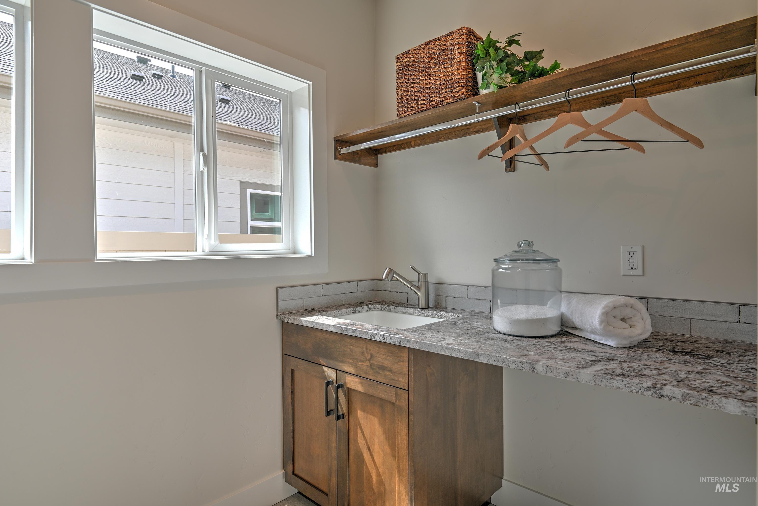 Laundry room with a sink and baseboards