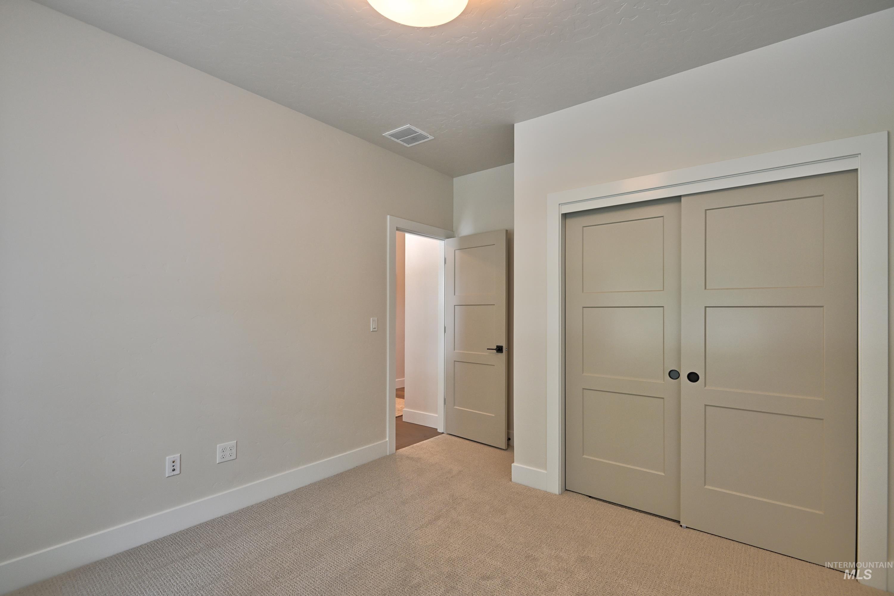 Unfurnished bedroom with light carpet and a closet