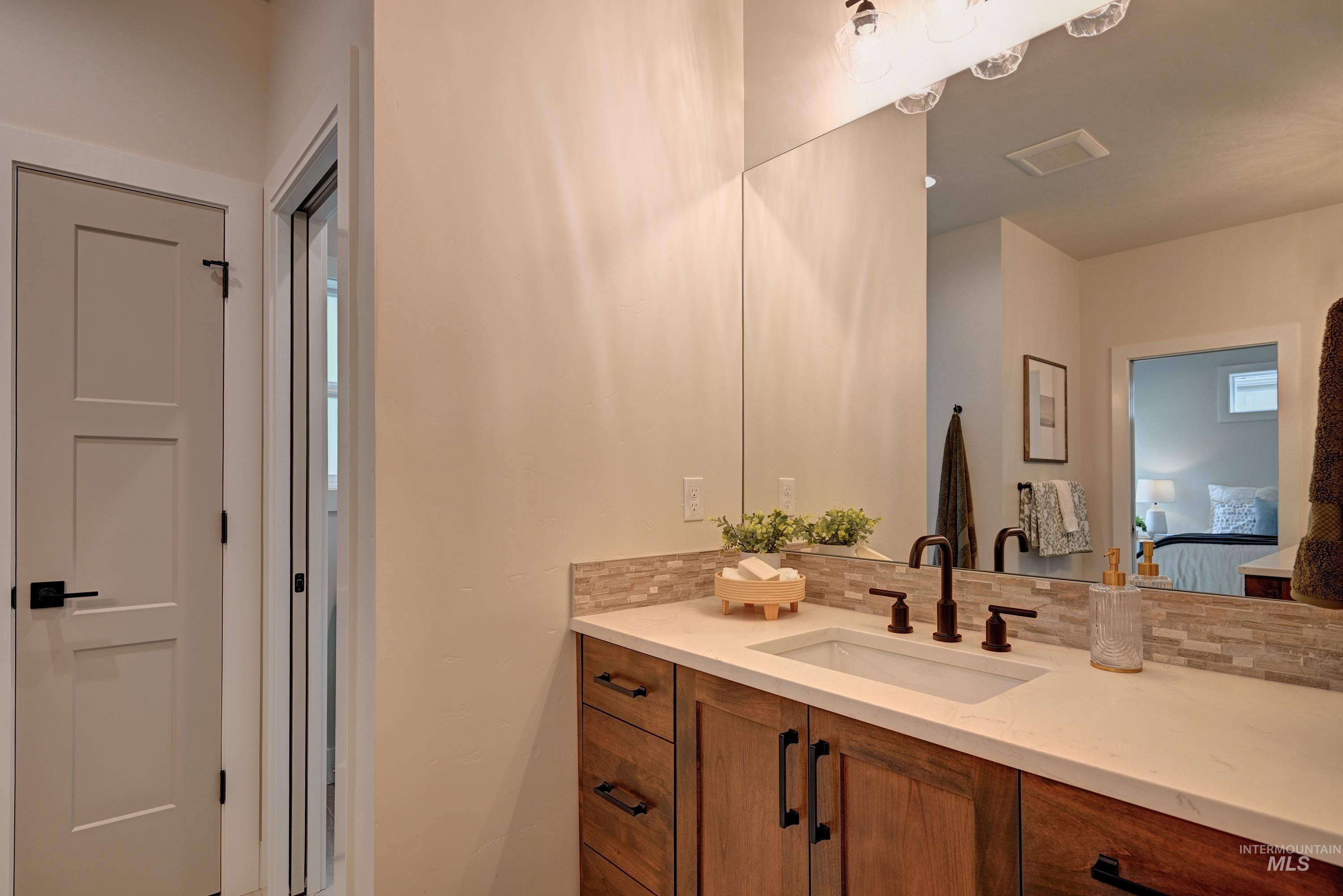 Ensuite Bathroom with quartz counters, tile backsplash, custom alder wood built cabinets and dual vanities