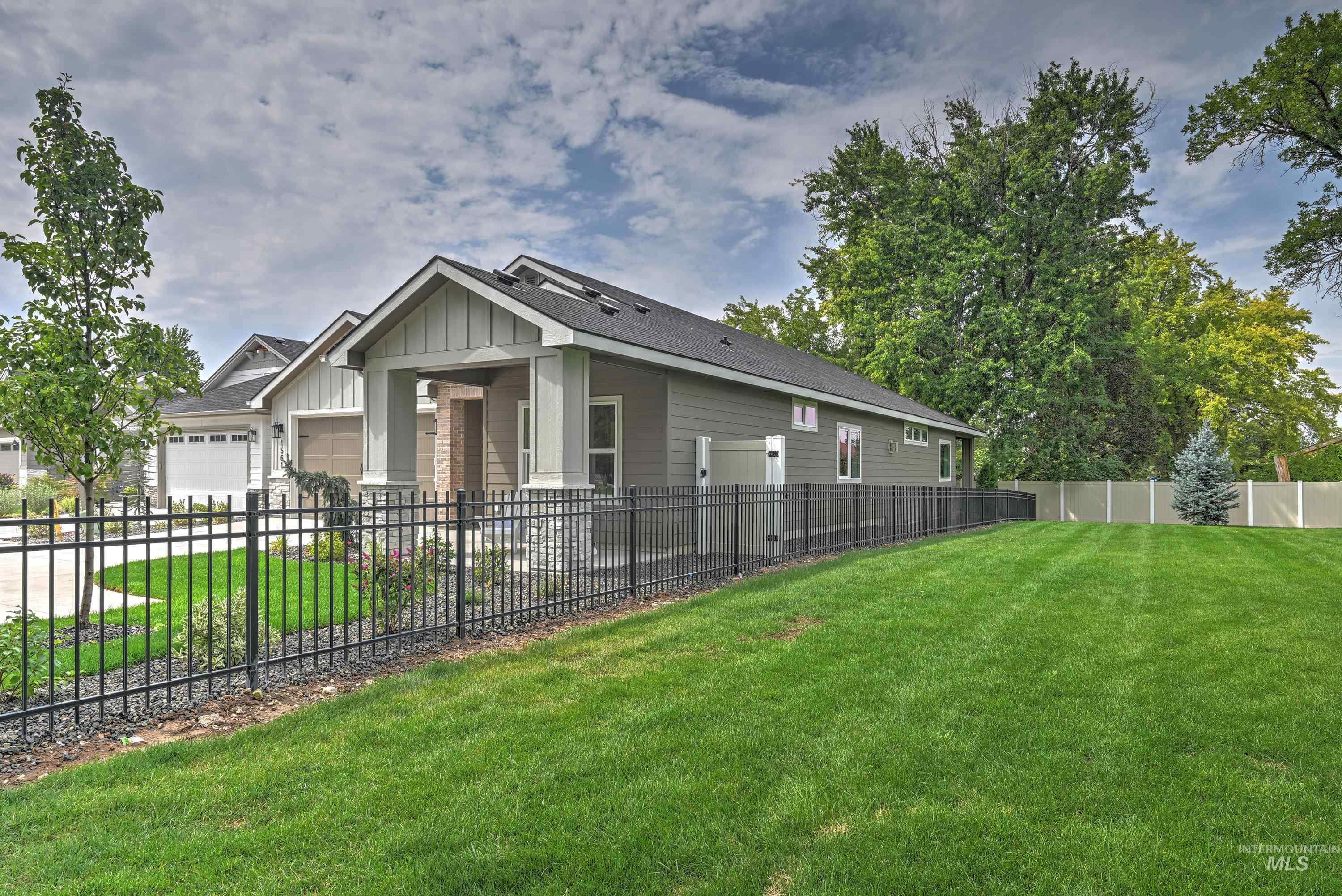 View of front of home with a fenced front yard, a garage, and board and batten siding with stone & brick accents
