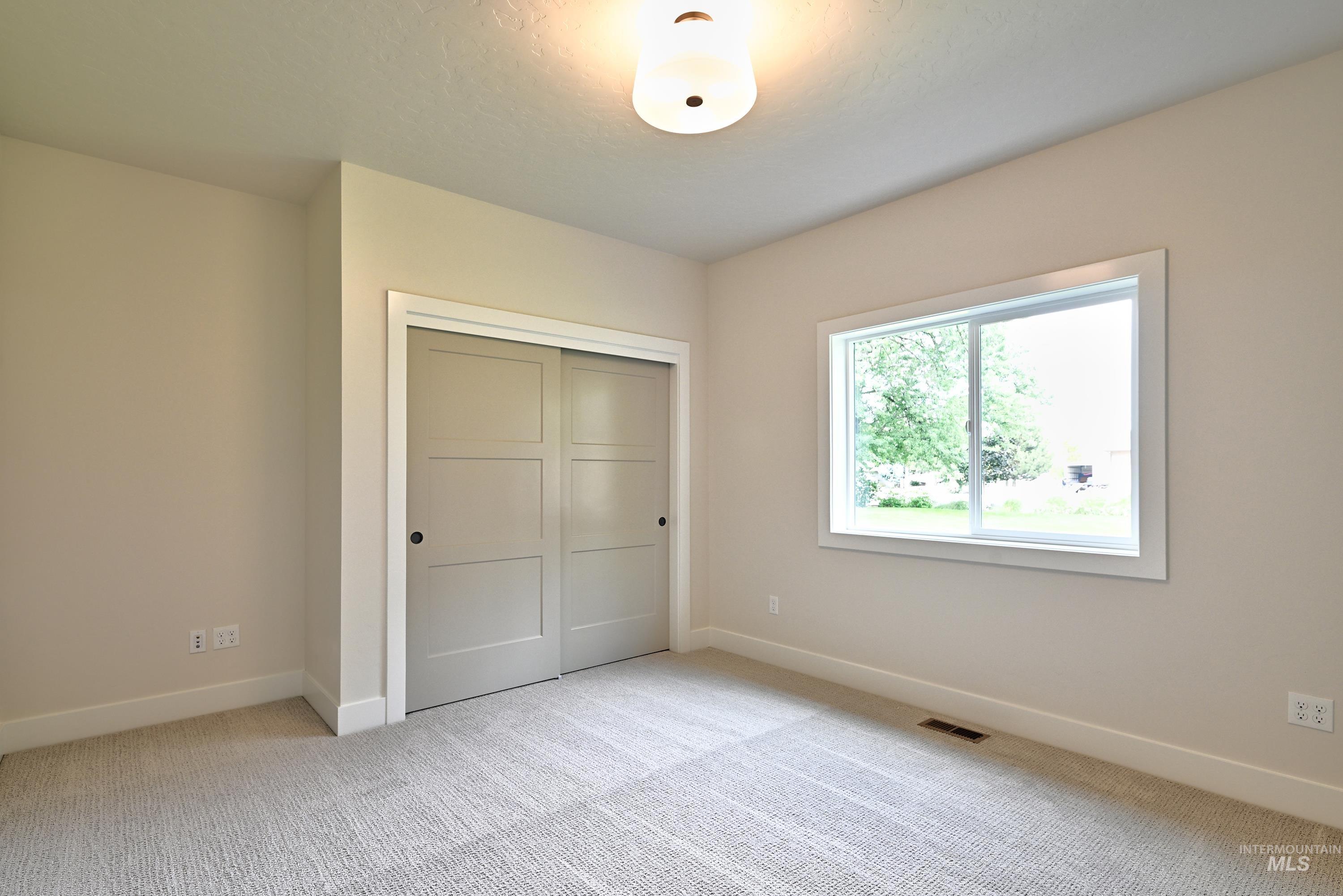 Unfurnished bedroom featuring light carpet and a closet