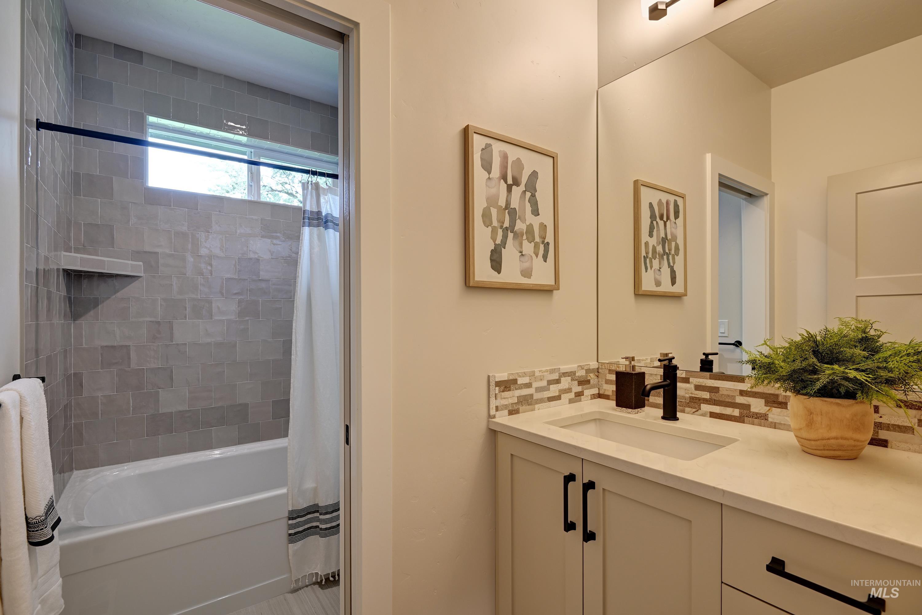 Full bath featuring tile backsplash, vanity, and shower / bathtub combination with curtain