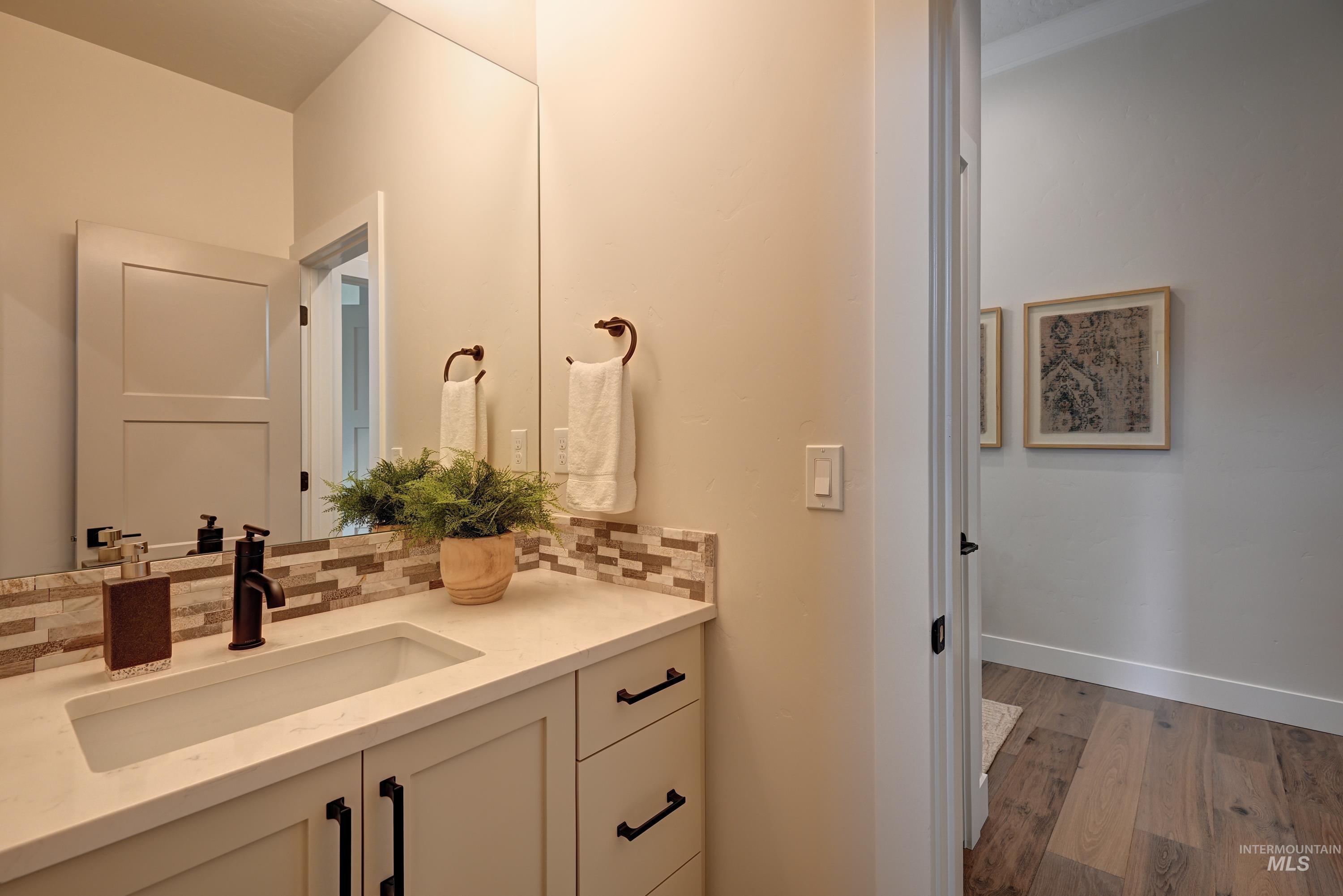 Bathroom featuring decorative tile backsplash, light wood finished floors, and vanity
