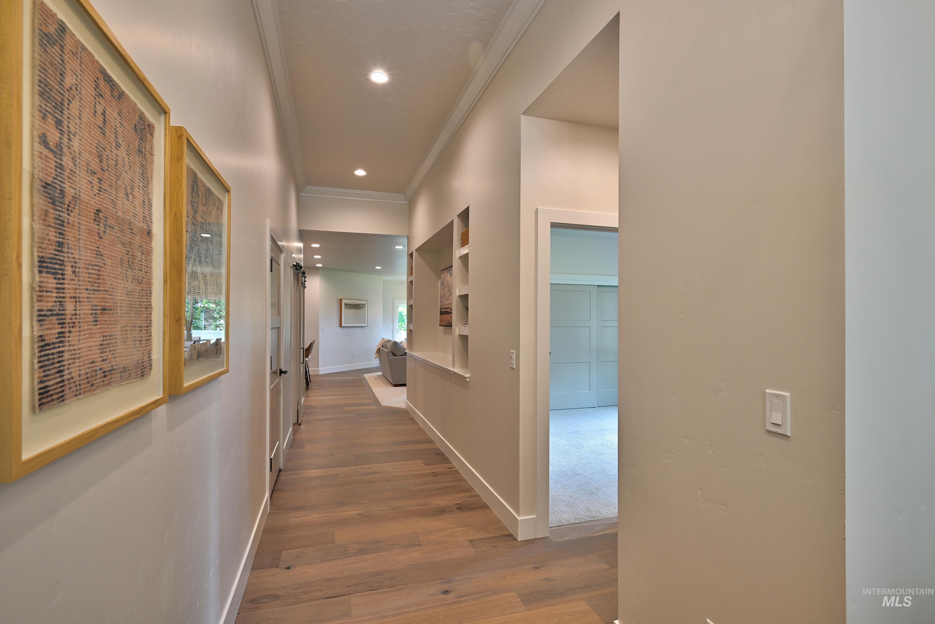 Hall with light wood-style floors, ornamental molding, and recessed lighting