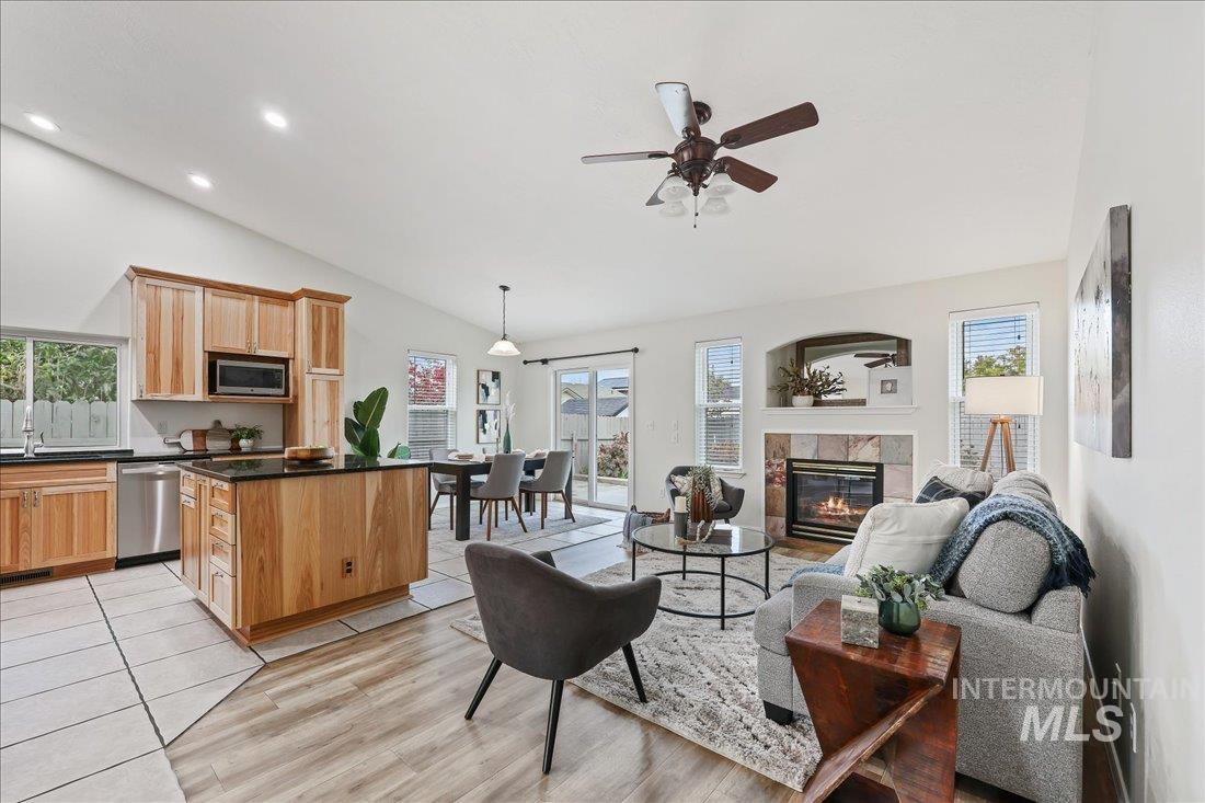 Living room featuring a fireplace, a ceiling fan, plenty of natural light, light wood-type flooring, and high vaulted ceiling