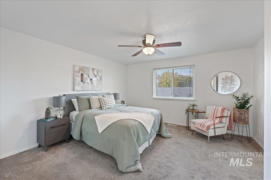 Carpeted bedroom featuring ceiling fan and a textured ceiling
