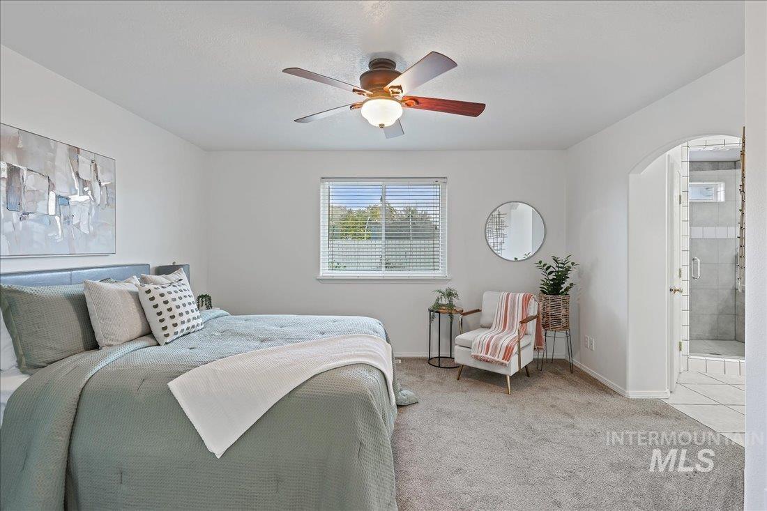Bedroom with carpet, ceiling fan, arched walkways, and ensuite bath