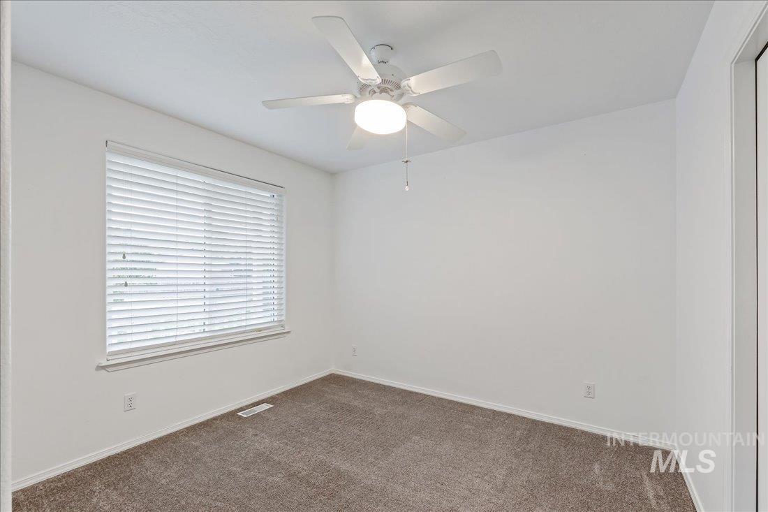 Empty room with carpet floors and a ceiling fan