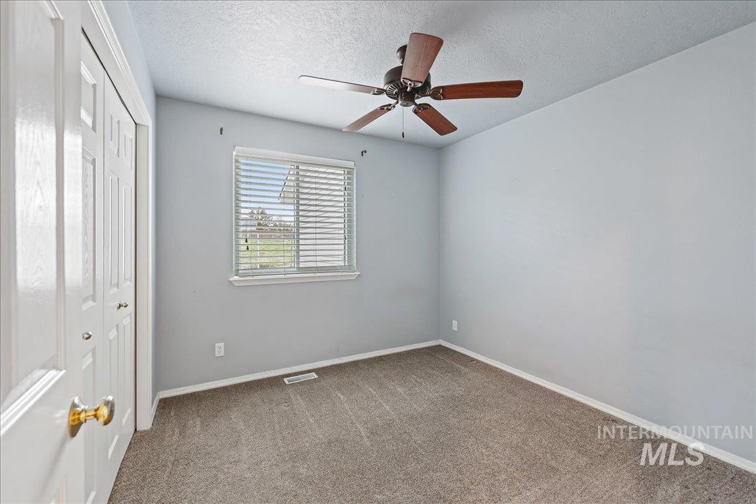 Unfurnished bedroom with a closet, a textured ceiling, carpet flooring, and ceiling fan