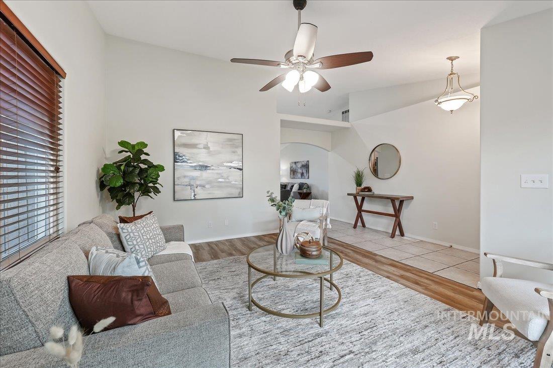 Living room featuring wood finished floors, a ceiling fan, lofted ceiling, and arched walkways