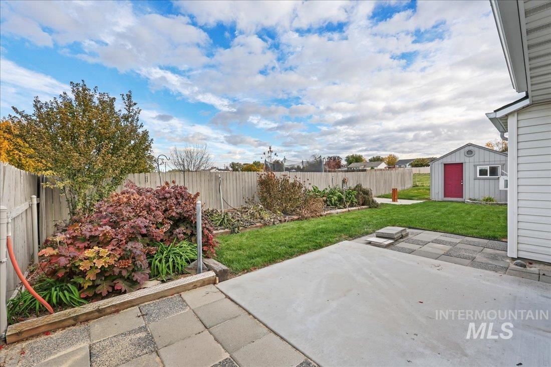 Fenced backyard featuring a patio area and a shed