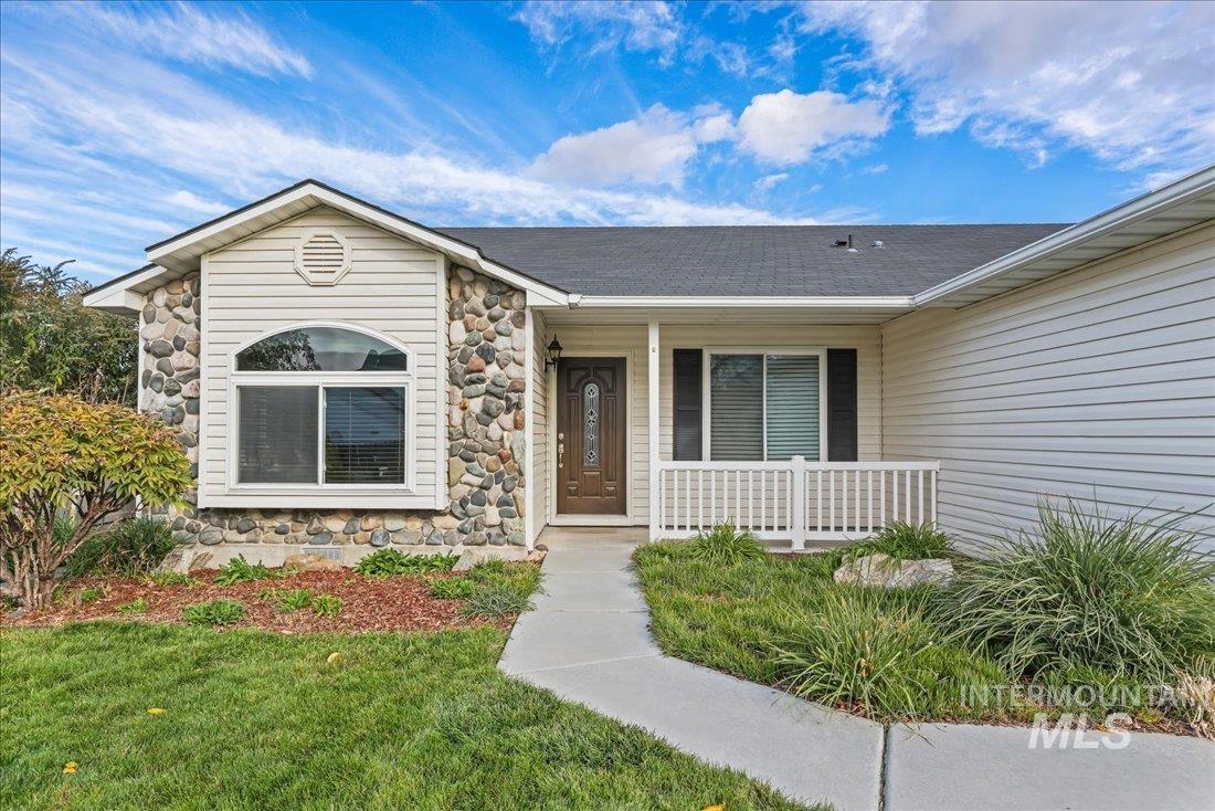 View of exterior entry featuring a porch, stone siding, and a yard
