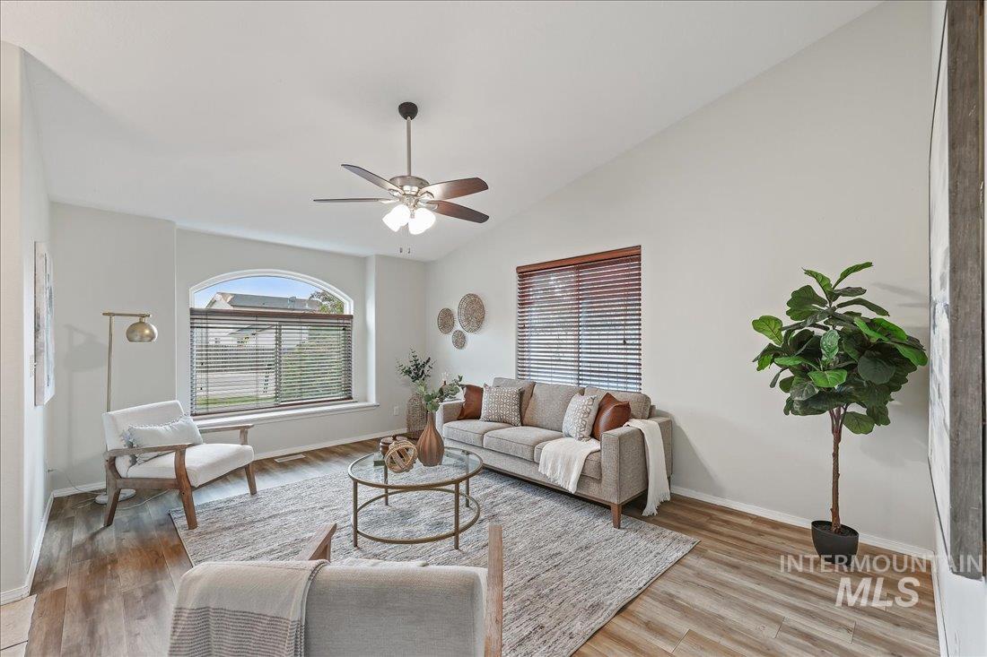 Living area featuring light wood-style floors, a ceiling fan, and vaulted ceiling