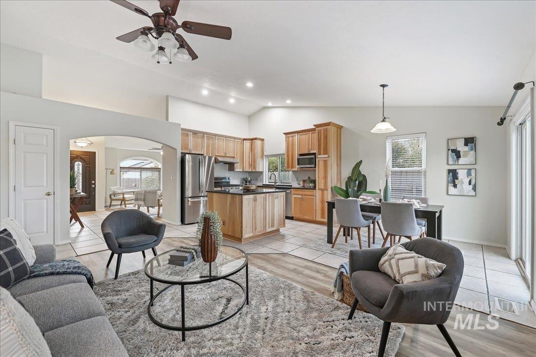 Living room featuring arched walkways, light wood-type flooring, lofted ceiling, plenty of natural light, and recessed lighting