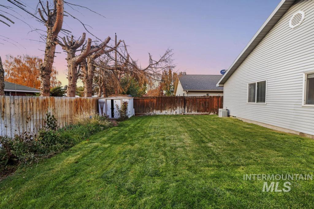 Yard at dusk with a fenced backyard and a shed