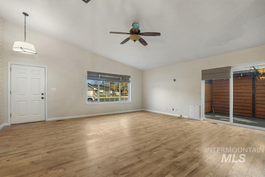 Unfurnished living room featuring lofted ceiling, hardwood / wood-style flooring, and a ceiling fan