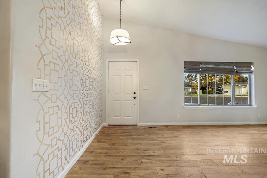 Foyer entrance with light wood-style floors and vaulted ceiling