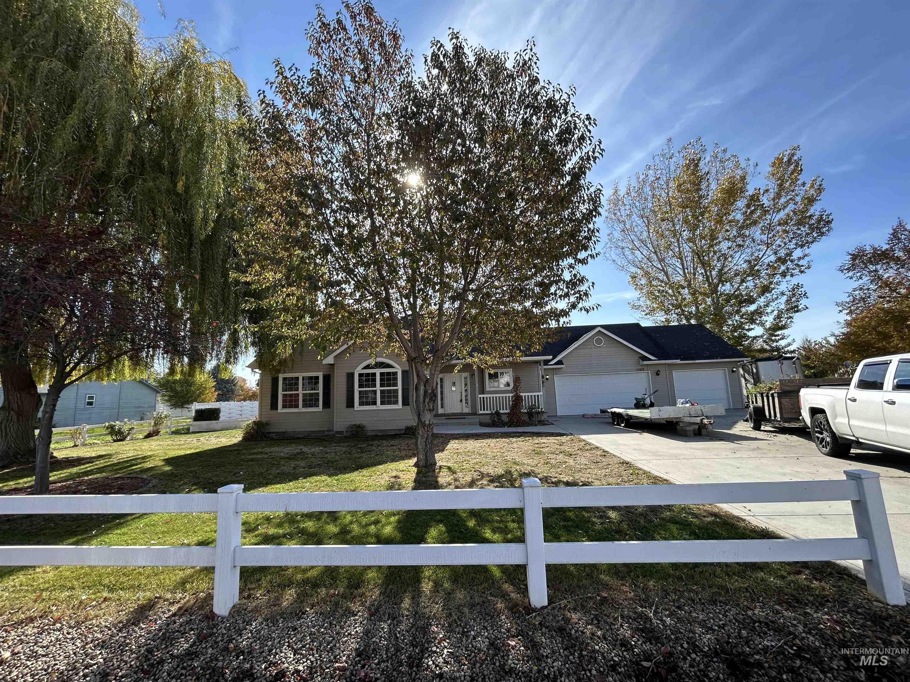 Ranch-style house featuring a fenced front yard, concrete driveway, and an attached garage