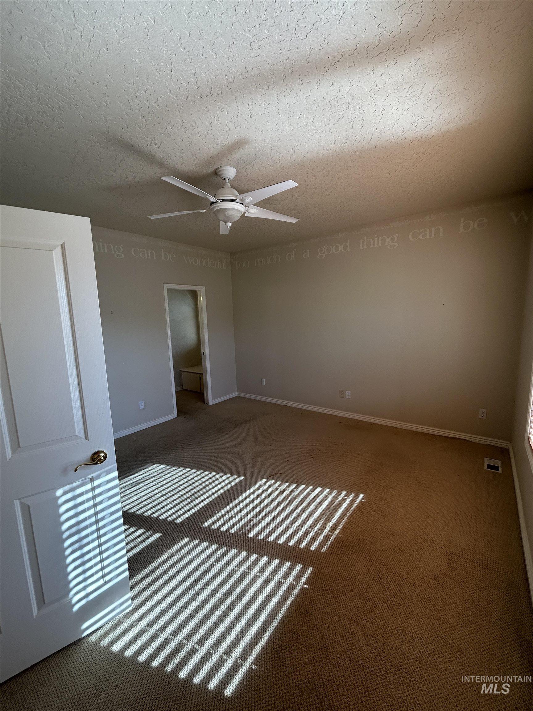 Unfurnished bedroom featuring carpet flooring, a textured ceiling, and ceiling fan