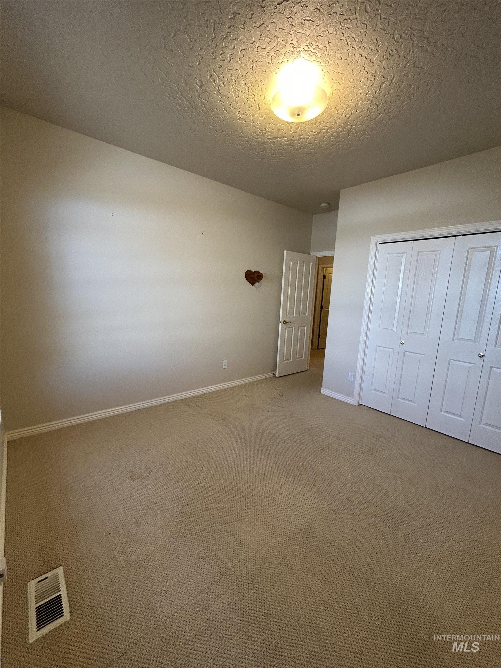 Unfurnished bedroom featuring a textured ceiling, carpet floors, and a closet