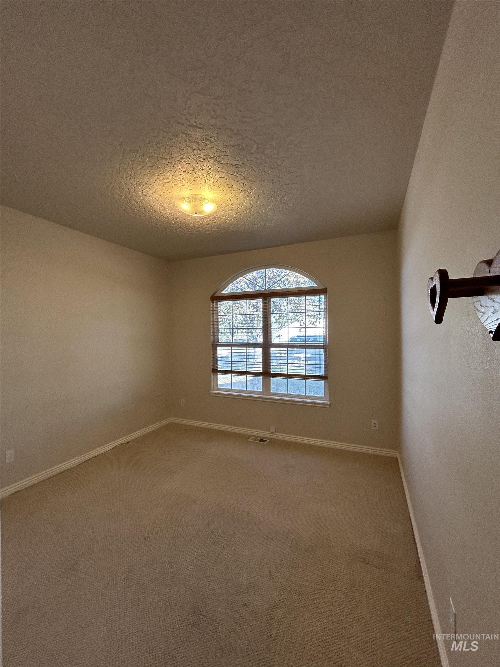 Empty room featuring a textured ceiling and carpet
