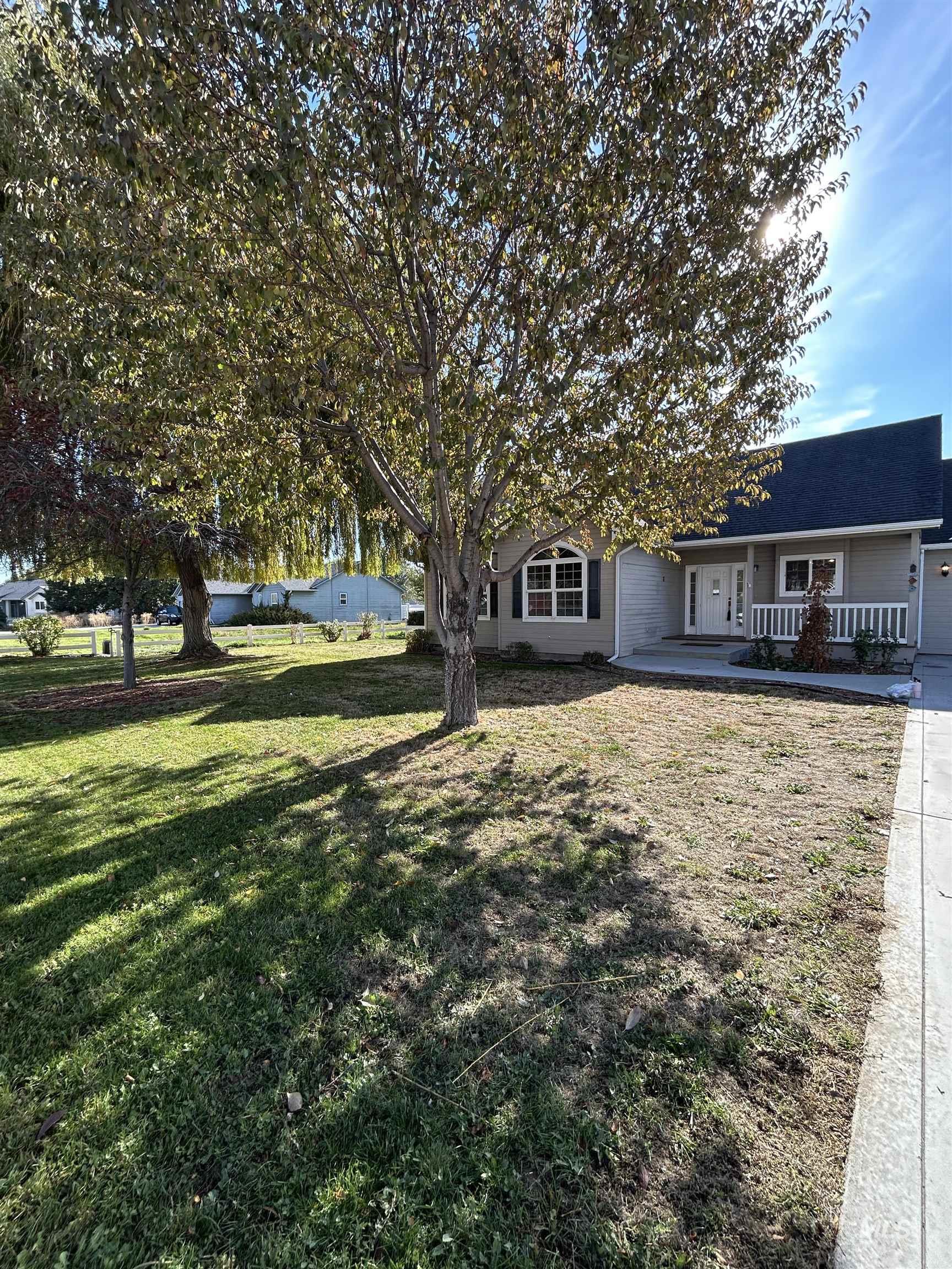 View of green lawn with covered porch, concrete driveway, and a garage