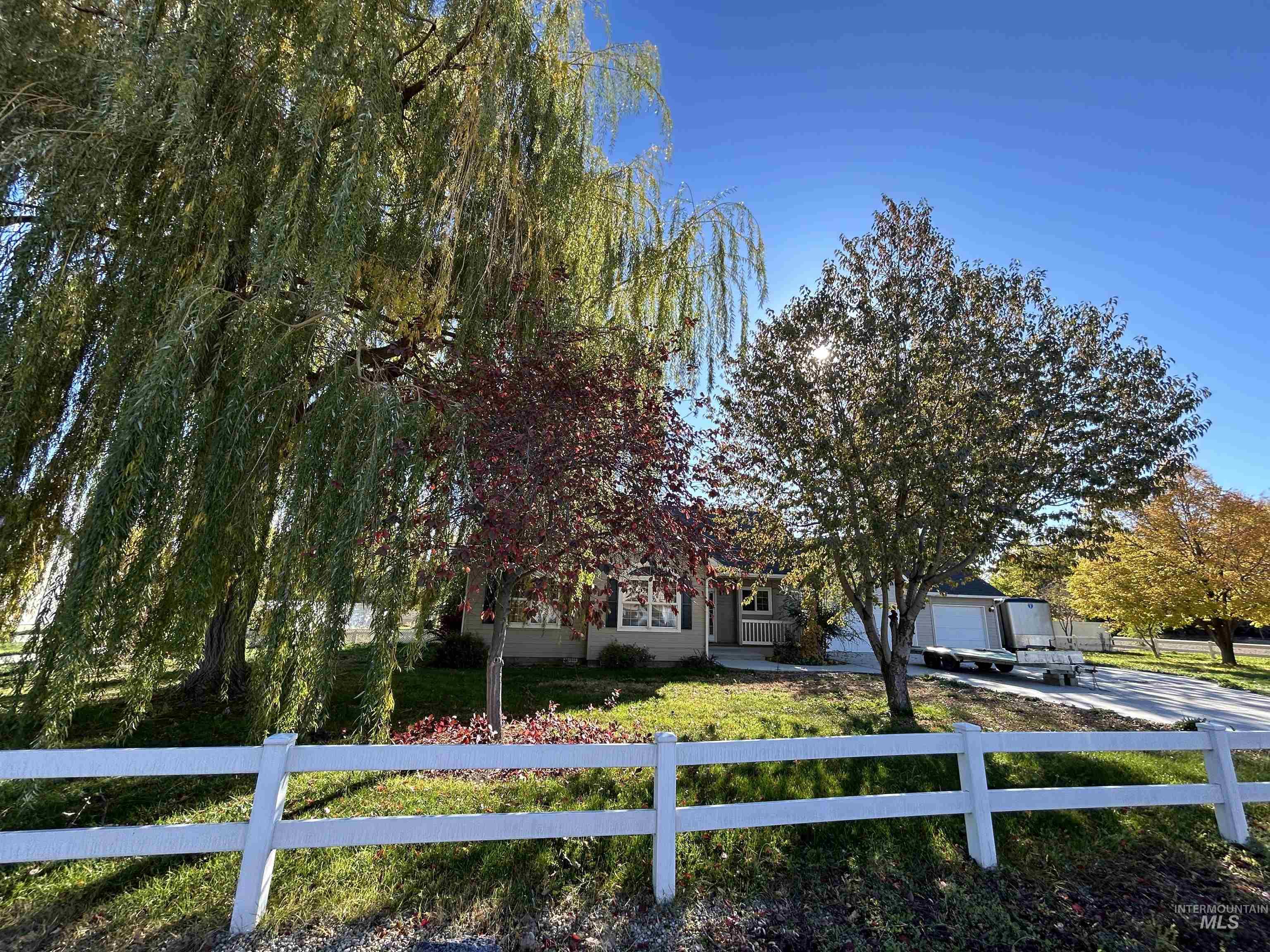 View of property hidden behind natural elements featuring a fenced front yard, concrete driveway, and a garage