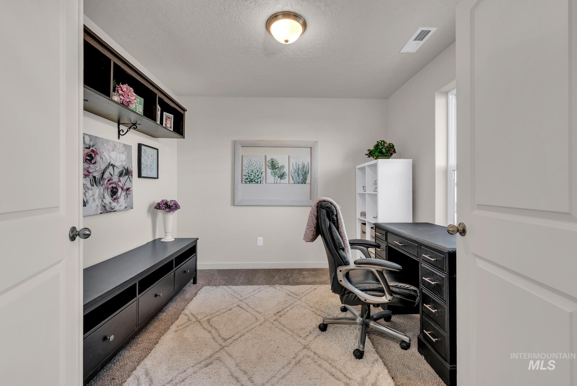 Home office featuring light carpet and a textured ceiling