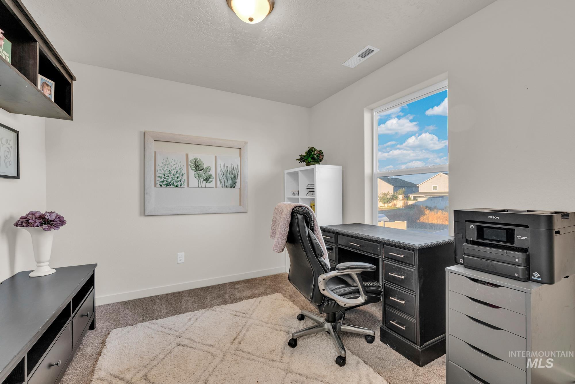 Office with light colored carpet and a textured ceiling