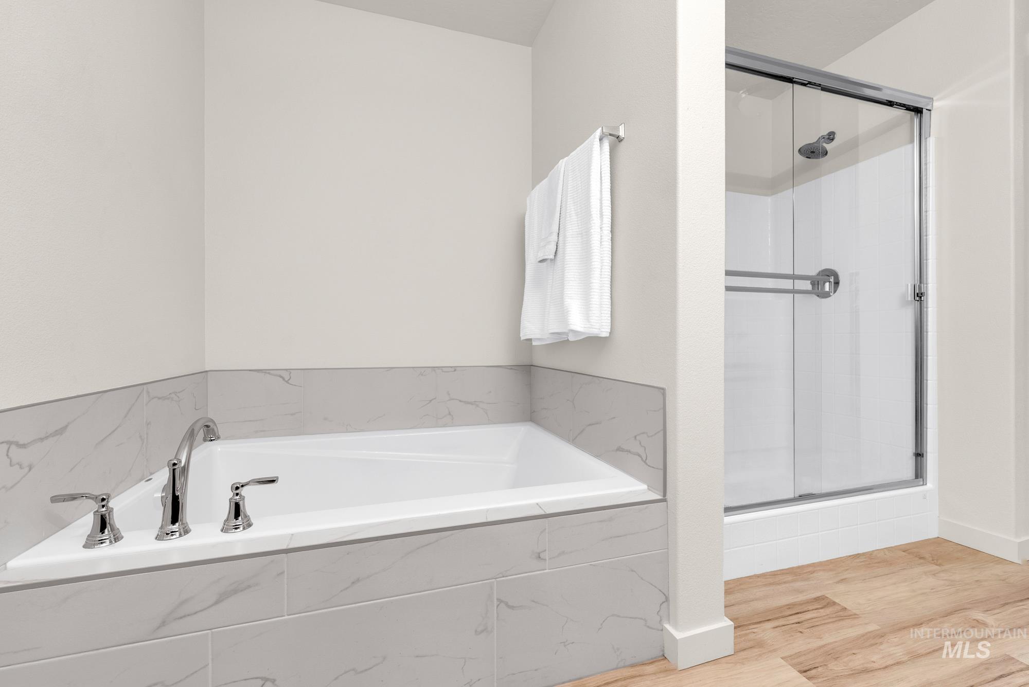 Full bath featuring light wood-type flooring, a stall shower, and a bath