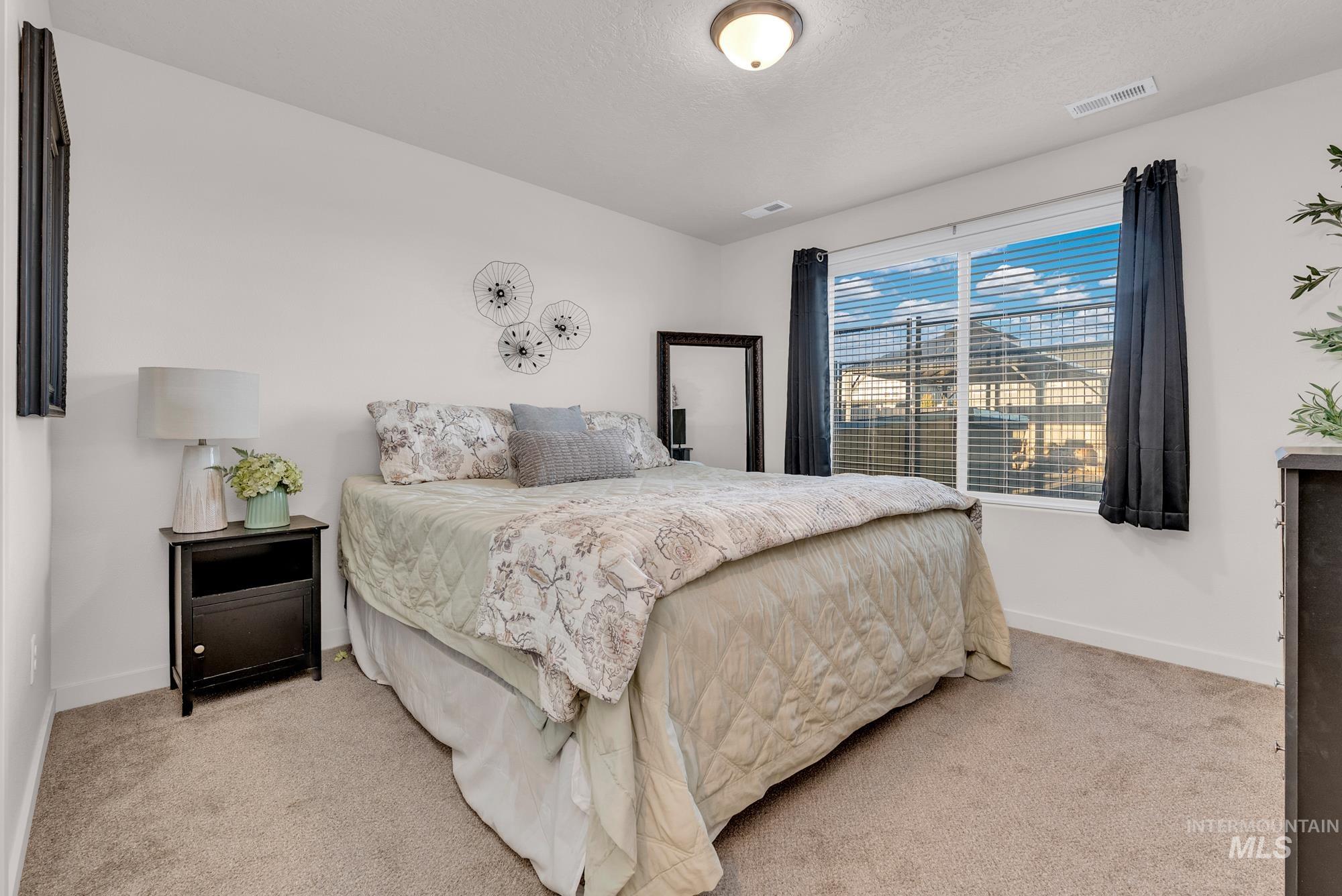 Bedroom featuring light colored carpet and a textured ceiling