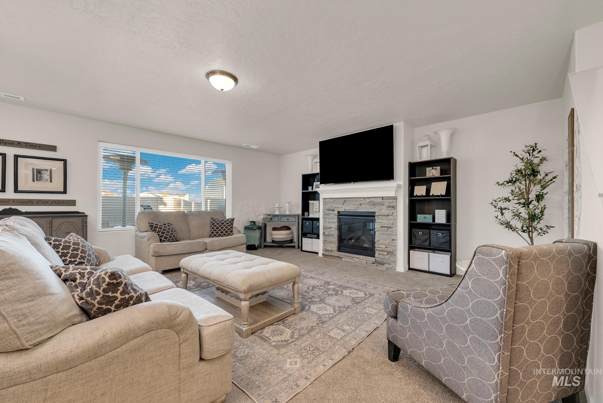 Carpeted living area featuring a fireplace and a textured ceiling