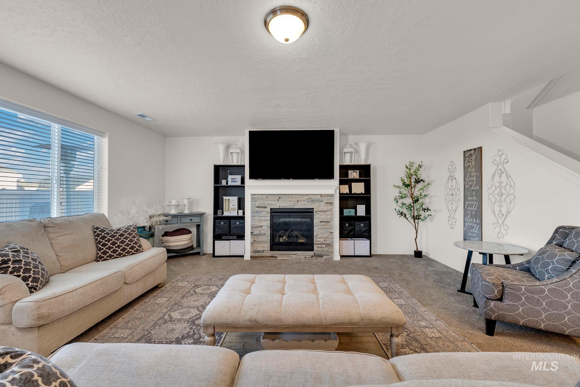 Carpeted living area with a textured ceiling and a stone fireplace