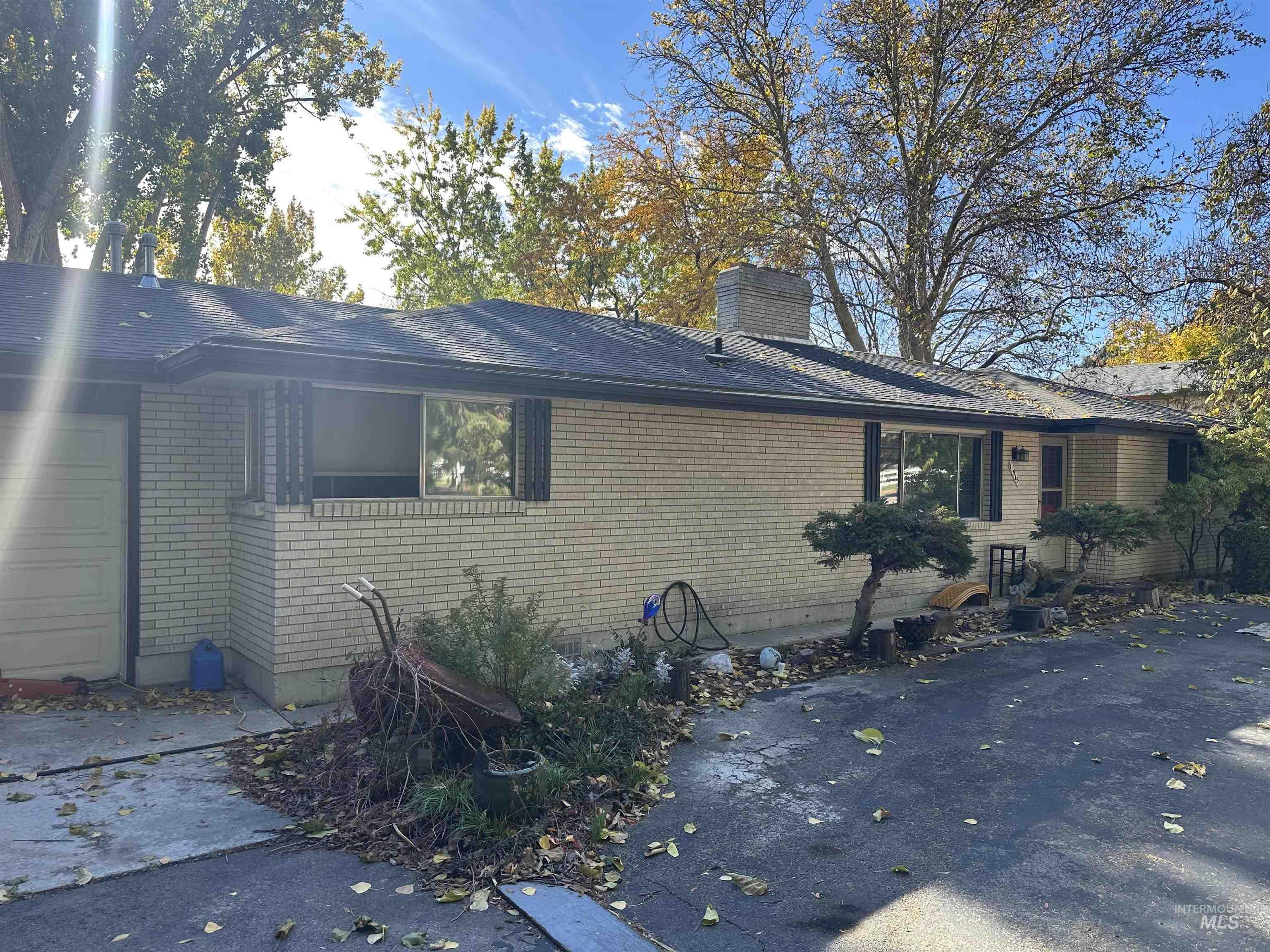 View of side of home with brick siding, a chimney, a garage, and roof with shingles