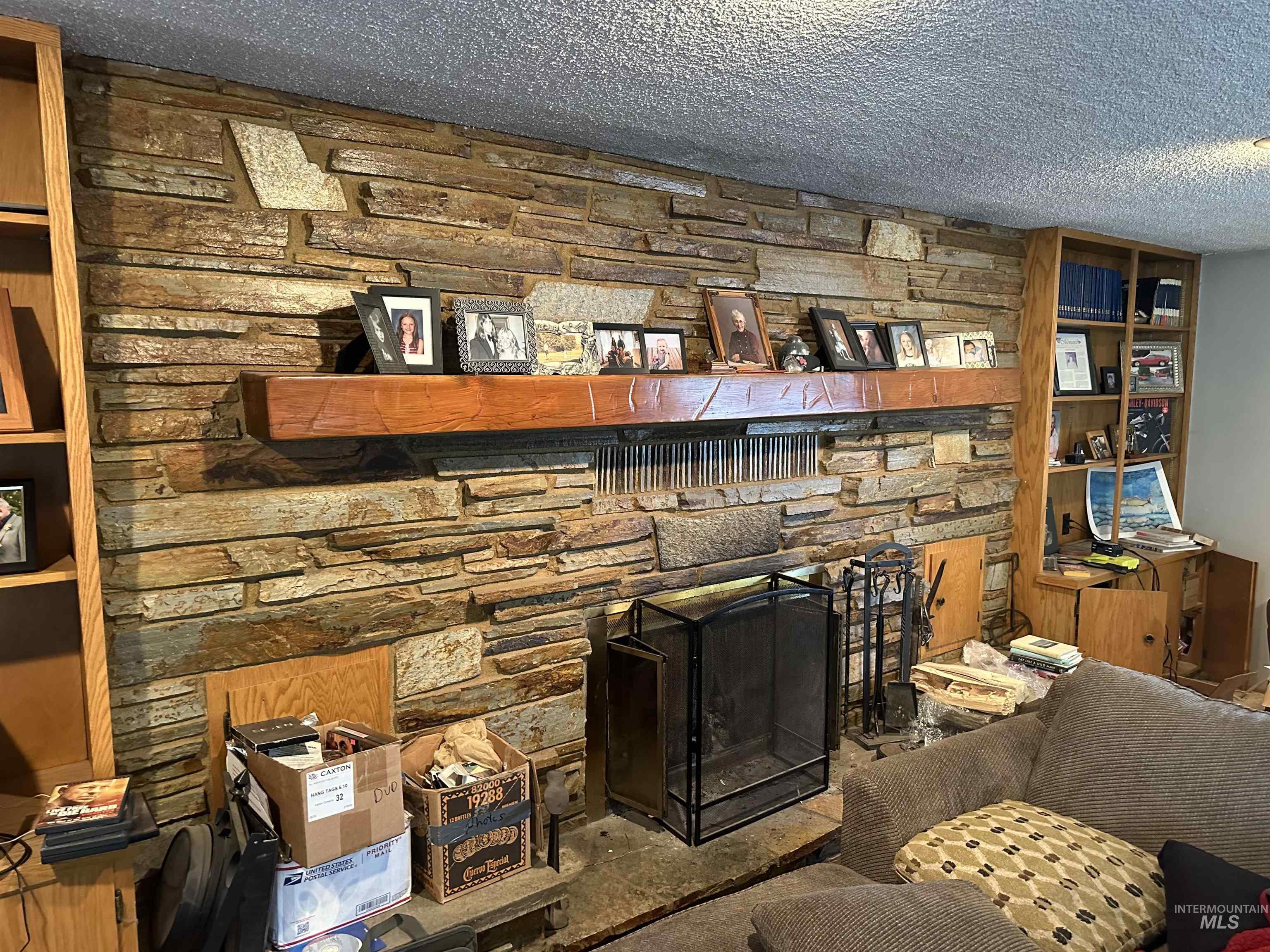 Detailed view of a stone fireplace and a textured ceiling