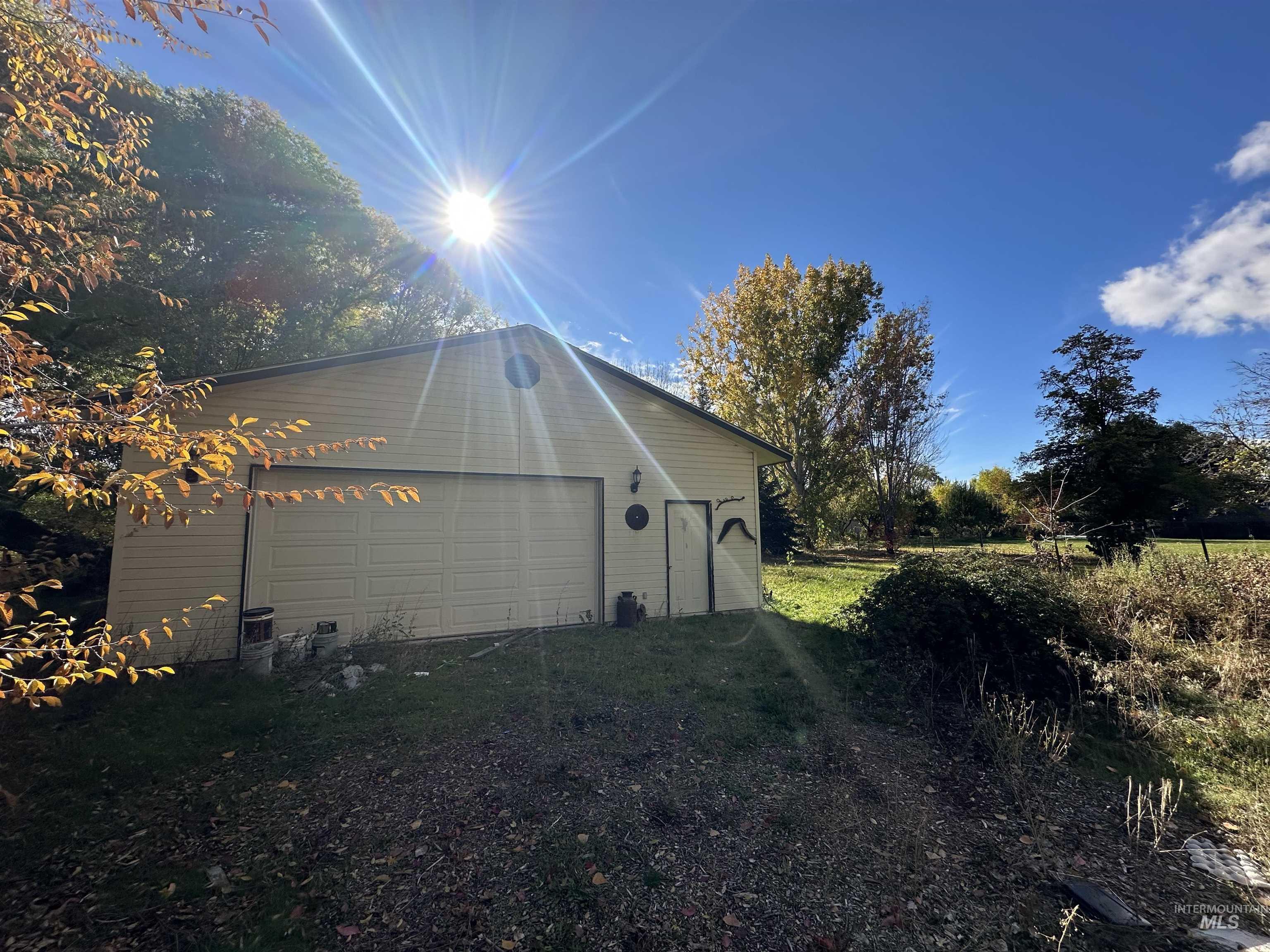 View of side of home featuring a garage and an outbuilding