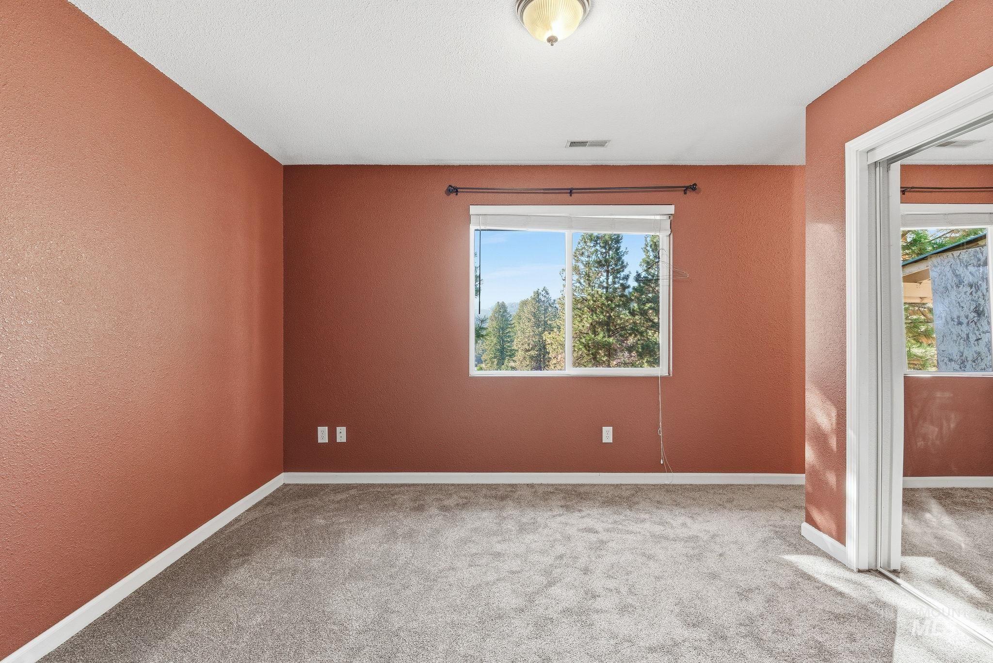 Empty room with a textured wall, carpet flooring, and plenty of natural light