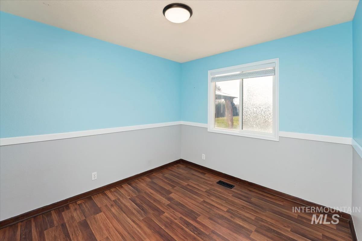 Empty room featuring dark wood-style flooring and baseboards